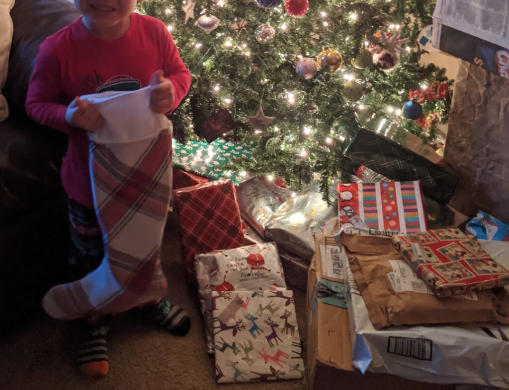 Toddler with stocking in front of tree