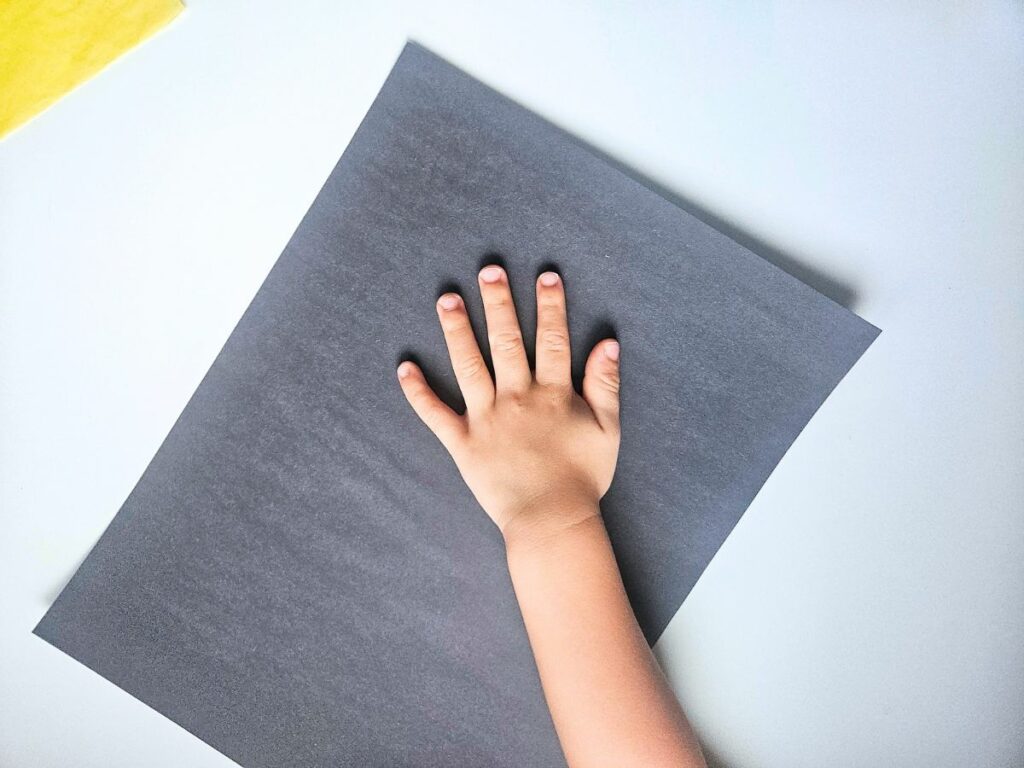 Tracing a child's handprint on black paper