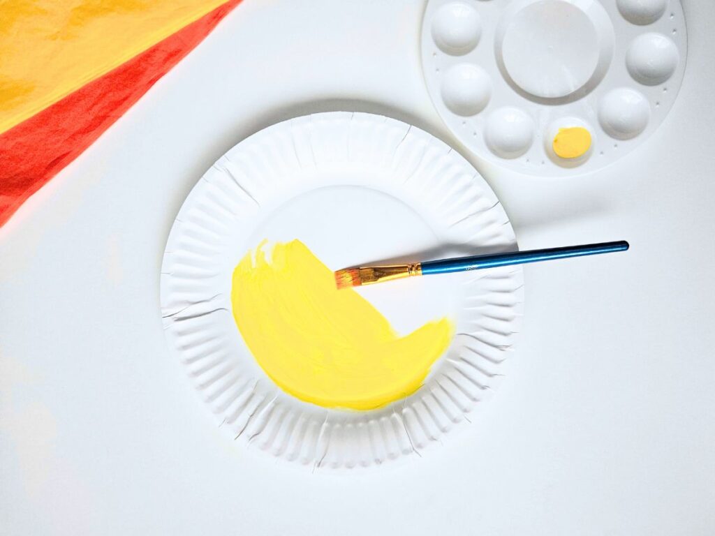 Paper plate being painted yellow