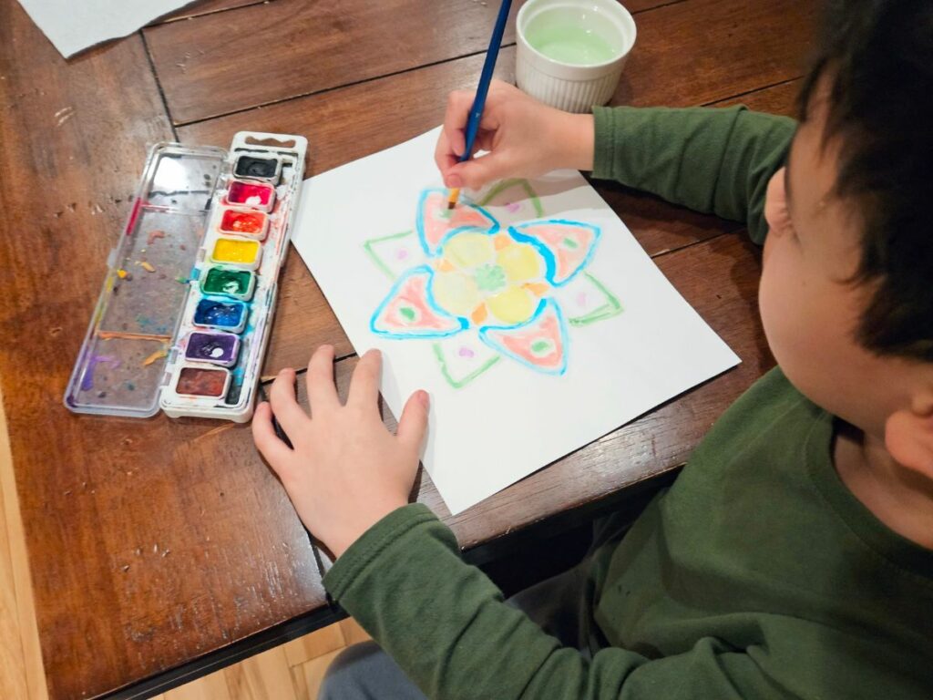 Child watercoloring a mandala craft