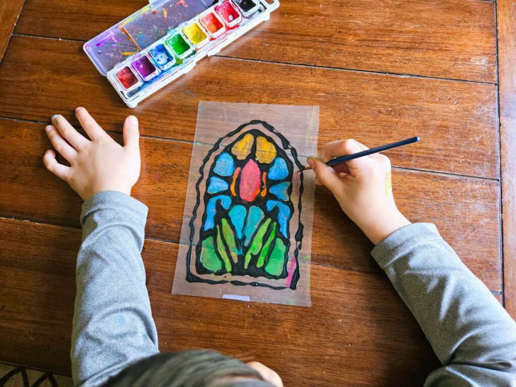 Child painting their stained glass window craft